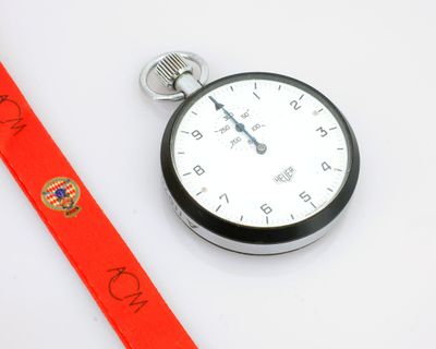 une montre de poche en argent entourée d'un ruban rouge