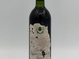 an old bottle of wine sitting on top of a white table