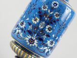 a blue vase with flowers on it sitting on a table