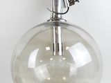 a clear glass vase with a metal handle on a white surface