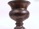 un vase en métal posé sur une surface blanche