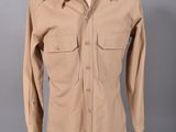 une chemise beige posée sur un mannequin, sur fond gris