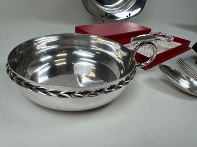 a silver bowl with a spoon and a fork on a table