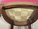 three wooden chairs with pink upholstered cushions sit on a tile floor