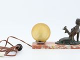 a statue of a woman sitting on a rock next to a lamp