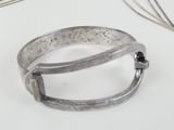 a silver bracelet with a chain around it on a table