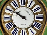 a gold clock with blue and white stripes on the face