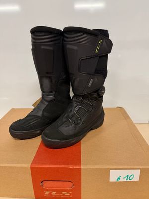 des bottes de moto noires posées sur une boîte en carton posée sur une table