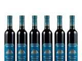 quatre bouteilles de vin rouge sont alignées sur un fond blanc