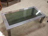une table en verre avec une base en métal et un plateau en verre