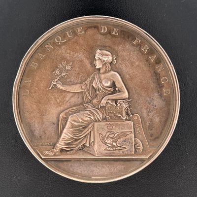 une image représentant une médaille d'argent sur laquelle figure une femme assise sur une boîte