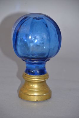 a blue glass vase with a gold base on a table