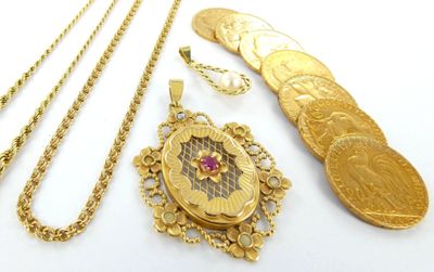 plusieurs colliers en or et une pièce d'or posés sur une surface blanche