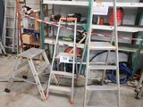 Plusieurs échelles sont empilées dans un garage, avec des outils posés dessus.
