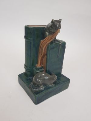 a cat sitting on a bookend with a cat on top of it