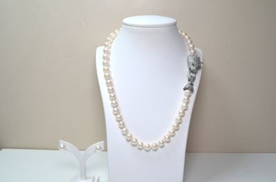 un mannequin blanc portant un collier de perles et une broche en forme de fleur