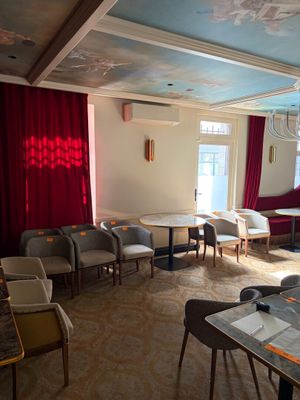 des tables et des chaises dans une pièce où des rideaux rouges sont suspendus au plafond