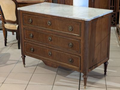 a marble top chest of drawers in the middle of a room