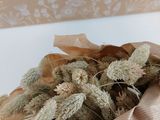 des fleurs séchées dans un sac en papier kraft posé sur une table blanche