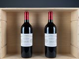two bottles of red wine in a wooden box on a table