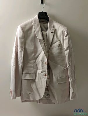 une veste blanche suspendue à un cintre devant un mur blanc