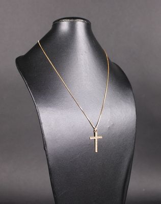un collier avec une croix en or autour du cou d'un mannequin