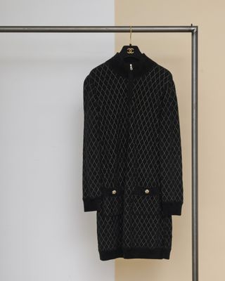 un manteau noir suspendu à un porte-vêtements près d'un mur blanc