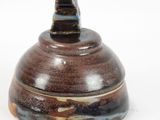 a brown and black bowl with a lid on a white surface