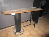a wooden table with a metal base on a tile floor