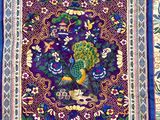 a close up of a purple and blue rug with a peacock on it