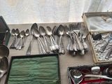 a lot of silverware on a table with a window in the background