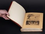 someone is holding a book open on a black table