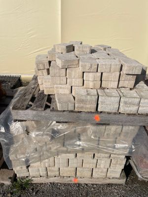 un tas de briques posé sur une palette à côté d'un bâtiment