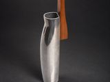 un vase en argent muni d'une poignée en bois, sur fond noir