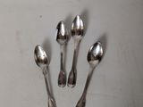 four silver spoons are arranged in a row on a white surface