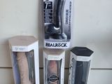 trois types différents de sextoys, rangés dans des boîtes posées sur une table