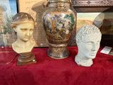 trois vases et un buste posés sur une table rouge