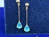 une paire de boucles d'oreilles en or ornées de cristaux bleus sur fond bleu