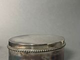 pair of silver plated boxes with beaded edges on a grey background