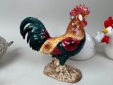 three figurines of roosters on a white table