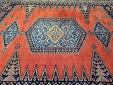 un tapis oriental orange et bleu orné d'un motif en losanges