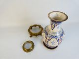 a blue and white vase with a gold ring on it