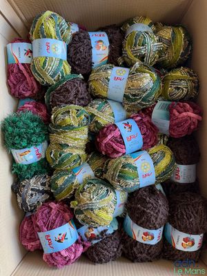 une boîte remplie de nombreuses pelotes de laine de différentes couleurs