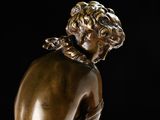a bronze statue of a boy sitting on a rock
