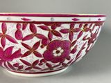 a pink and white bowl with a floral design on it