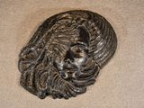 a metal sculpture of a man ' s face on a beige surface