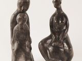 two sculptures of a man and a woman sitting on a chair