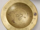 an antique brass ashtray with a fleur and a fleur on it