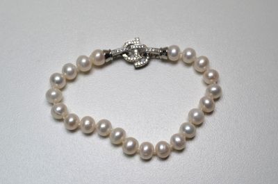 a close up of a white pearl bracelet with a silver clasp