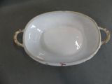a white bowl sitting on a table with a gold handle